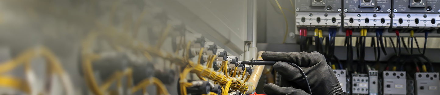 Technician using multimeter inside control panel, emphasizing maintenance and electrical safety